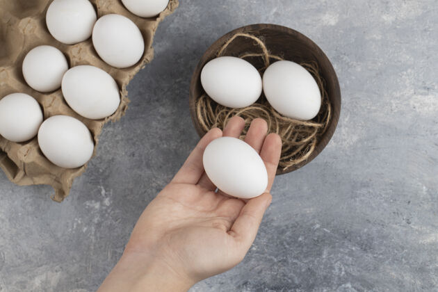 鸡一个女人手拿一个新鲜的白色鸡蛋放在大理石背景上鸟餐堆