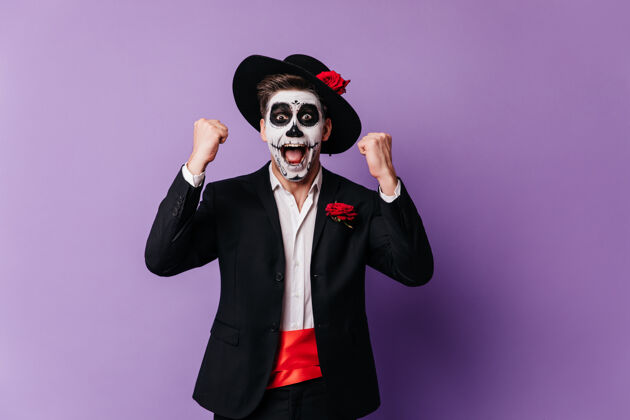 文化用墨西哥恐怖化妆品表达幸福的快乐男人快乐的年轻男模庆祝死亡日的摄影棚照片节日恐怖花