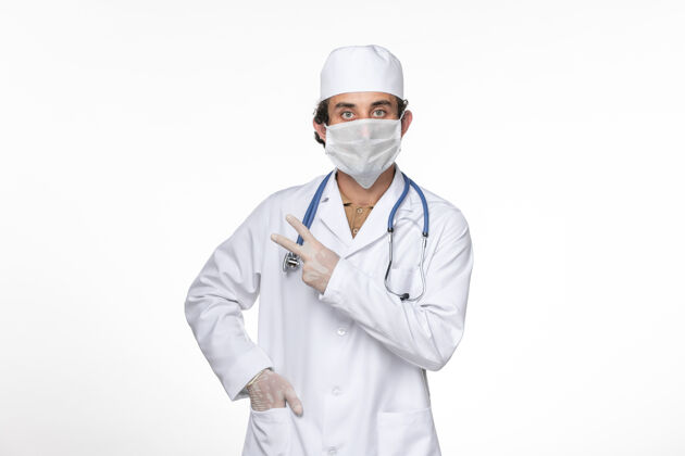医疗正面图身穿医疗服的男医生戴着防冠状病毒口罩在白色办公桌上冠状病毒大流行药实验室外套外套防护