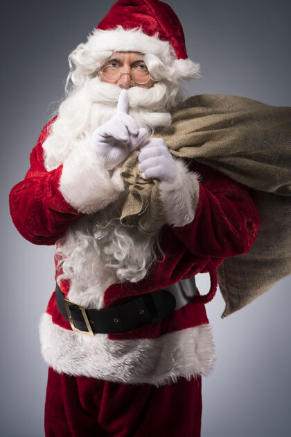 手指对嘴带着礼物袋的圣诞老人男性传统庆祝活动