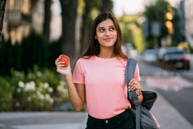 成人一个拿着苹果的年轻女子的画像 背景是街道户外水果人