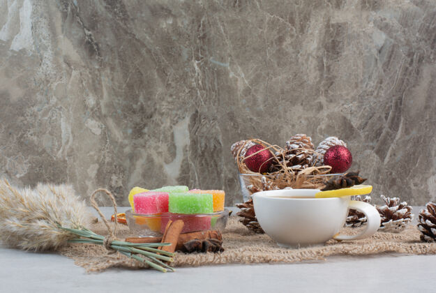 红球甜甜的糖果和美味的茶在麻布上高品质的照片松果茶柠檬