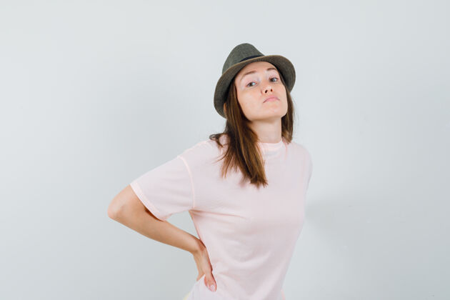 痛苦年轻女性穿着粉色t恤 戴着帽子背痛 看起来很累 正面照黑发休闲积极