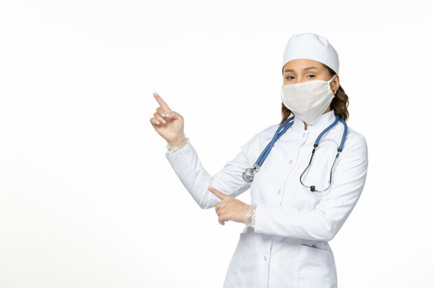 护士前视女医生身穿白色医疗服戴口罩因白色办公桌上冠状病毒大流行疾病隔离医生人员穿戴