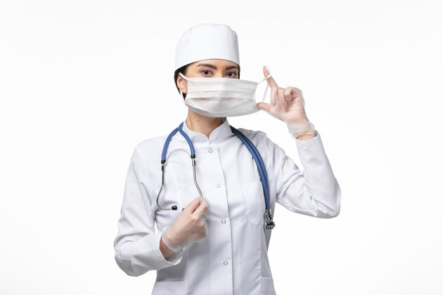 听诊器正面图女医生穿着白色无菌医疗服戴口罩因柯维德-白墙病柯维德-大流行病毒病专业外套女性