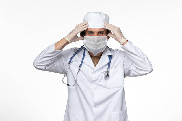 冠状病毒正面图男医生穿着医疗服 戴着无菌口罩 以防柯维德-强调白墙病毒疾病柯维德大流行疾病套装医疗大流行