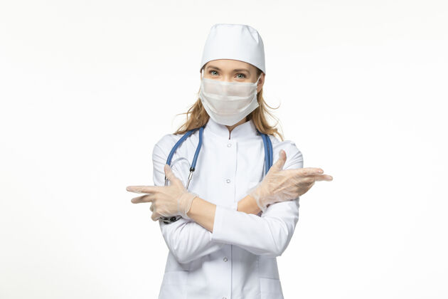 职业正面图女医生穿着医疗服戴着口罩戴着手套 因白墙上的冠状病毒大流行病毒套装冠状病毒女性
