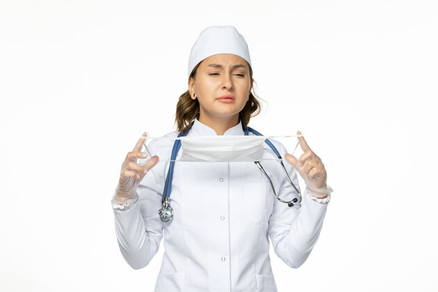 医生正面图女医生身穿白色医疗服手持口罩在白墙上大流行疾病药物病毒隔离人医疗持有