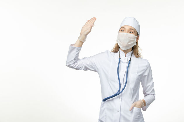 冠状病毒正面图：穿着白色医疗服 戴着白色口罩的女医生 在白色地板上抵御冠状病毒的侵袭微笑防护西装