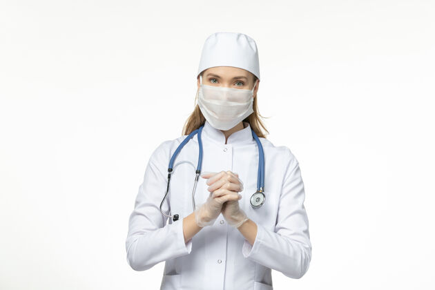 医生前视女医生身穿医疗服戴口罩因冠状病毒浅白桌病冠状病毒-大流行病毒病浅白色医务人员病毒