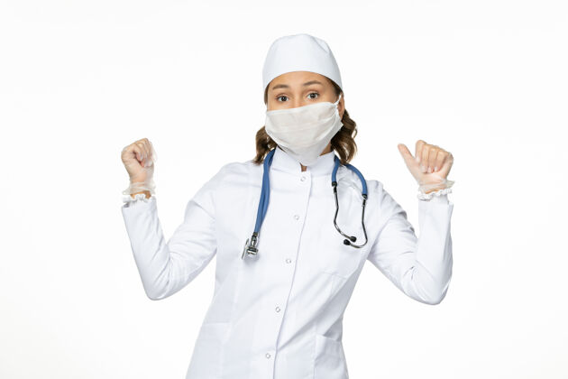 护士正面图女医生穿着白色医疗服 戴着口罩 因白色办公桌上有冠状病毒病隔离冠状病毒医疗制服居家