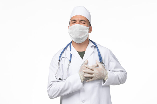 男性正面图：男医生 穿着医疗服 戴着口罩 因为冠状病毒-白墙心痛冠状病毒-病毒大流行病毒病到期专业磨损