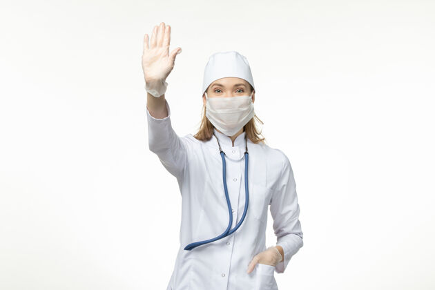 医生前视图：女医生穿着白色医疗服 戴着口罩 以防白墙上的冠状病毒感染人肖像人