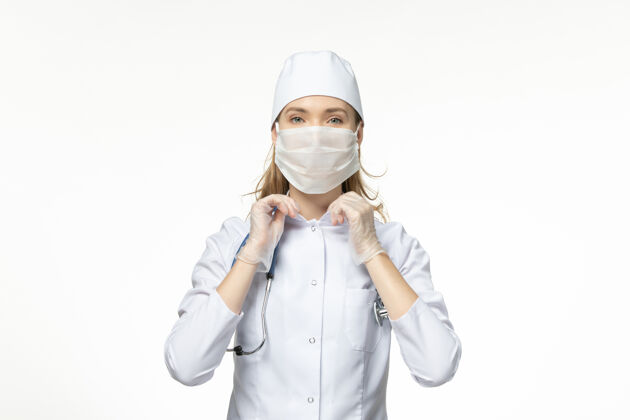 肖像前视图：女医生穿着白色医疗服 戴着防护面罩 由于白墙上有冠状病毒 疾病为冠状病毒-大流行性疾病防护套装疾病