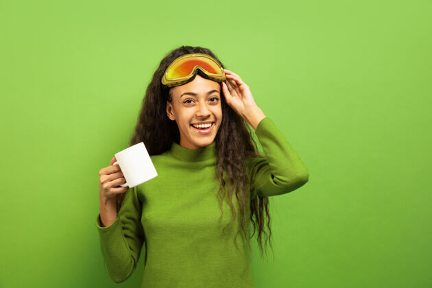 表情绿色空间里 一位黑人年轻黑发女子戴着滑雪面具的肖像黑发女士面具