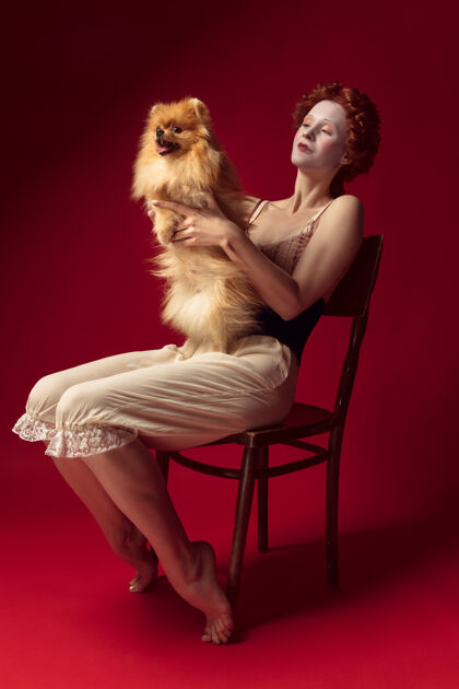 历史中世纪红发女公爵穿着黑色紧身衣和睡衣坐在椅子上的红色空间与小狗或狗衣服狗历史