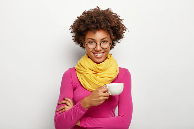 眼镜快乐表情的非洲裔美国女性肖像 戴眼镜 拿饮料杯 戴眼镜 粉色高领毛衣和围巾 孤立在白色背景上饮料深色浓咖啡