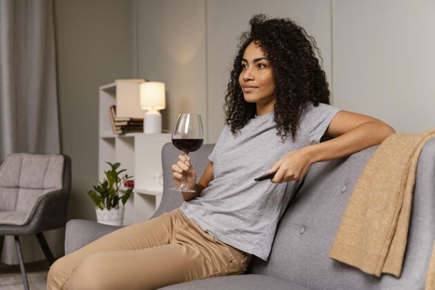 沙发坐在沙发上看电视喝酒的女人看电视女人电视遥控器