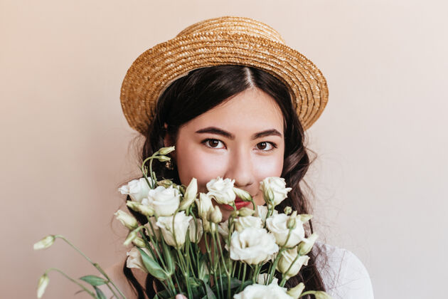 桔梗手持鲜花看着相机的韩国女士的肖像一个戴着草帽 长着白色桔梗的亚洲女人的摄影棚照片卷曲灵感米色隔离