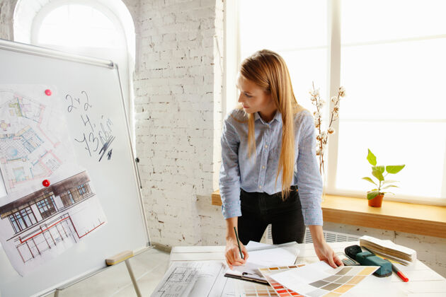 现代专业的室内设计师或建筑师在现代办公室中使用调色板 房间图纸样品选择工作场所
