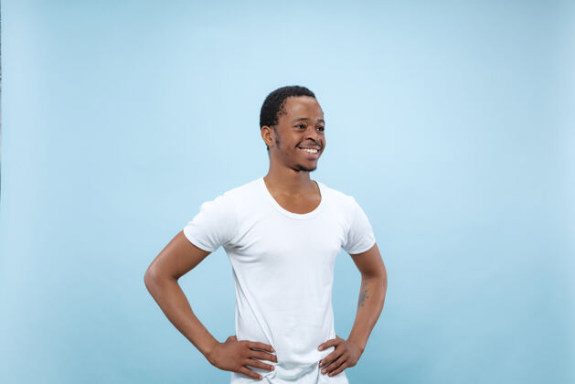 广告半身特写肖像的年轻非洲裔美国男子在白色衬衫的蓝色空间人类的情感 面部表情 广告概念男人商人衬衫