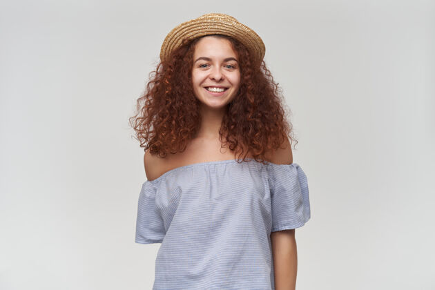 青少年十几岁的女孩 快乐的女人 卷曲的姜黄色头发穿着条纹露肩衬衫和帽子有一个大可爱的微笑隔着白墙孤立帽子卷发服装