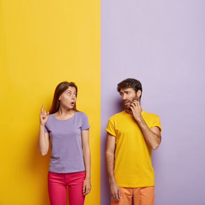 印象照片中情绪激动的女人试图向男人解释一些事情 上面点着震惊的表情 不悦的男人抓着猪鬃 穿着黄色t恤两个情人紫色