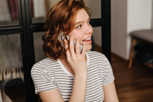 室内穿着条纹t恤的红色卷发女孩在电话里交谈的特写照片平板电脑肖像科技