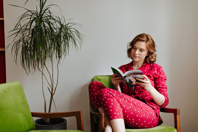 人穿着睡衣看书的沉思的高加索女人穿着红色睡衣的卷发年轻女人坐在扶手椅上发冷放松舒适专注