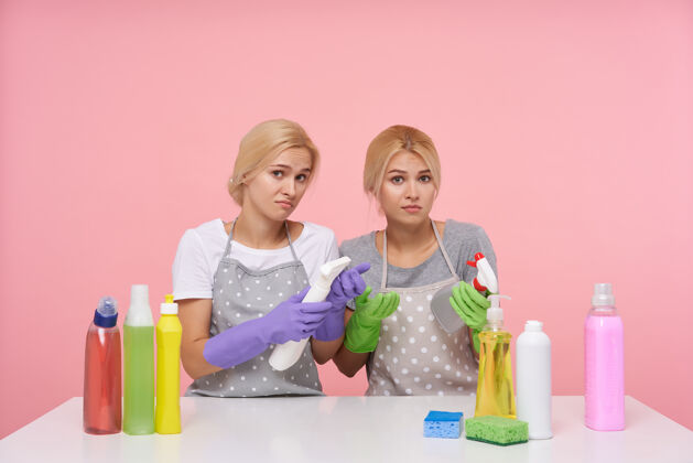 双胞胎年轻的金发可爱的主妇们戴着橡胶手套准备春季大扫除妹妹女性女士
