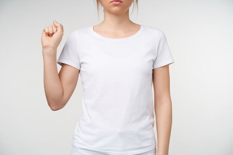 非语言摄影棚拍摄的年轻女性裸体修指甲握紧拳头 同时展示手语上的字母s 穿着白色t恤在白色背景下被隔离皮肤白皙成人翻译