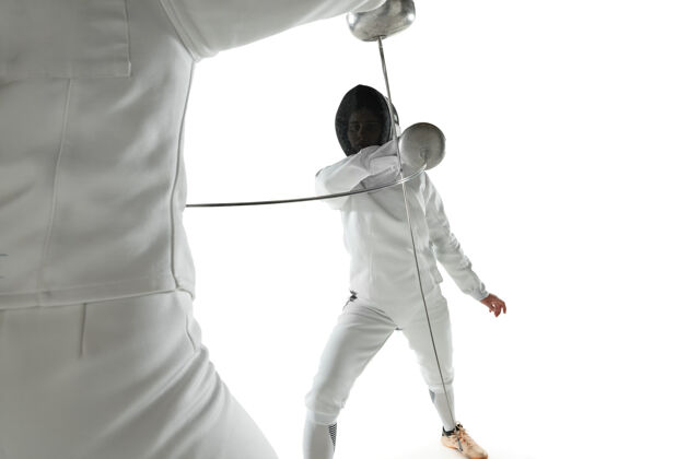 目标身着击剑服装的少女 手拿剑 与白色工作室背景隔离年轻的女模特练习和训练动作 动作复制空间战斗健康剑