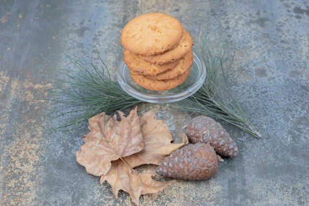 糕点美味的饼干放在玻璃罐里 叶子和松果放在大理石背景上高质量的照片美味杯子松果