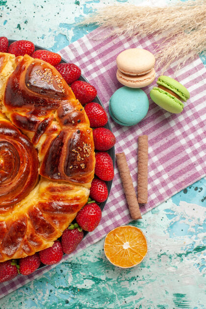 糖俯瞰草莓派与法国马卡龙在蓝色的表面食物顶午餐