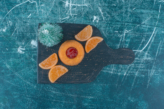 甜食果冻填充蛋糕 marmelades和一个树雕像在蓝色背景的黑色板上高质量的照片烘焙果冻果酱