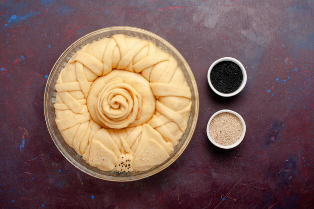 蛋糕顶视图：深紫色桌子上的生馅饼面团卡布奇诺线圈甜的