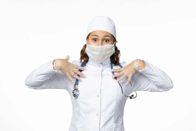 病毒正面图年轻的女医生戴着防护面罩 因为冠状病毒在浅白色的表面疾病制服工作