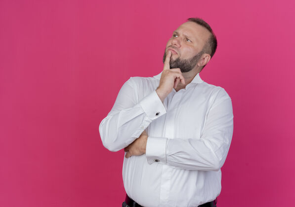 靠边一个留着胡子的穿白衬衫的男人站在粉红色的墙上 困惑地看着一边穿胡子拼图