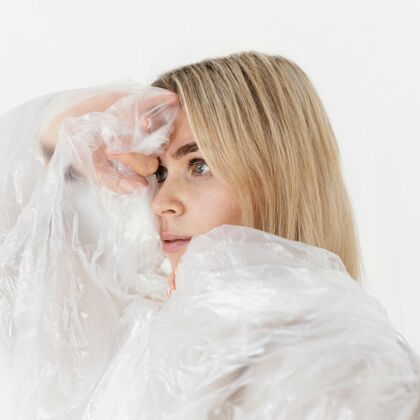 女人用塑料箔摆姿势的肖像女人模特年轻工作室
