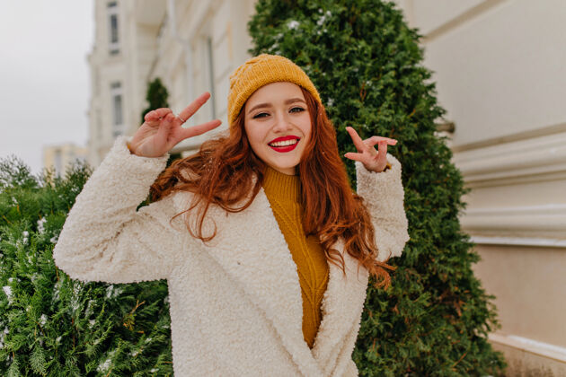 时尚优雅的姜女在享受冬天高兴的红发女孩在户外与和平标志合影红发模型时尚