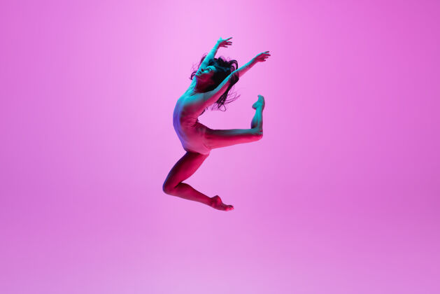 舞蹈年轻女孩在粉红色的墙上跳动作灵活芭蕾舞演员