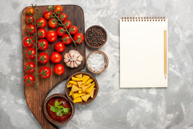 生的顶视图新鲜的樱桃番茄与不同的调味品和白色表面上的记事本不同顶部沙拉