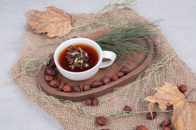 浆果一杯茶和干蔓越莓放在粗麻布上高质量的照片野生浆果茶草药