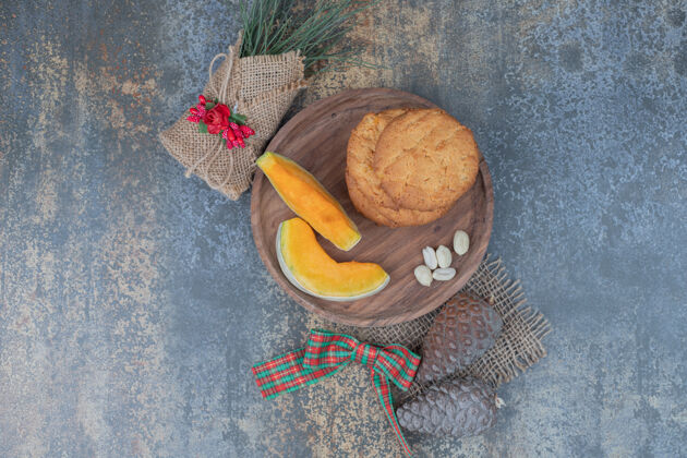 切片饼干和南瓜片放在装饰着丝带的木板上高质量的照片可食用松果南瓜