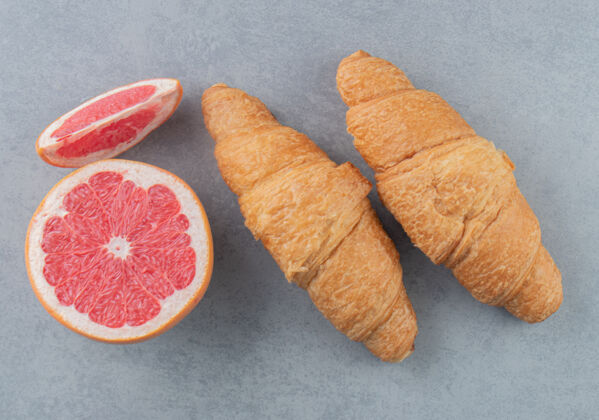 牛角包在大理石背景上切柚子和羊角面包高品质照片糖牙粉甜食