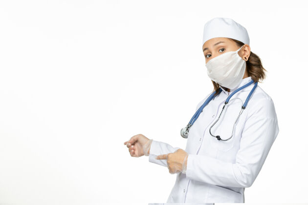 到期正面图年轻女医生戴着无菌口罩和手套由于白色表面有冠状病毒病毒药品正面