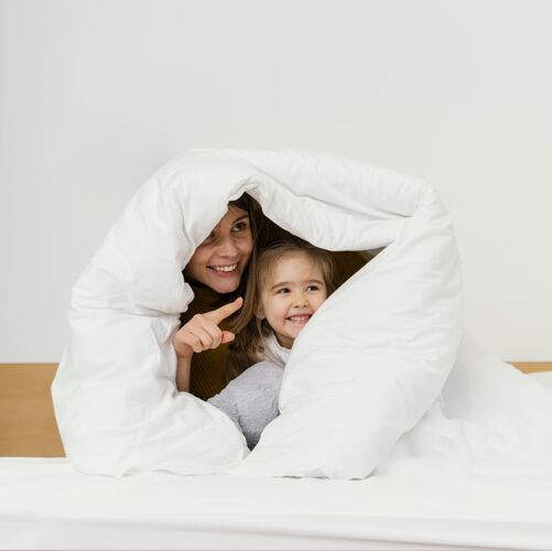 乐趣笑脸妈妈和孩子躲在毯子下面女人童年父母
