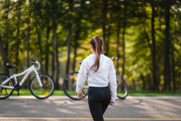 自行车美丽的女孩在白色自行车前摆姿势在大自然中漫步自然女人姿势