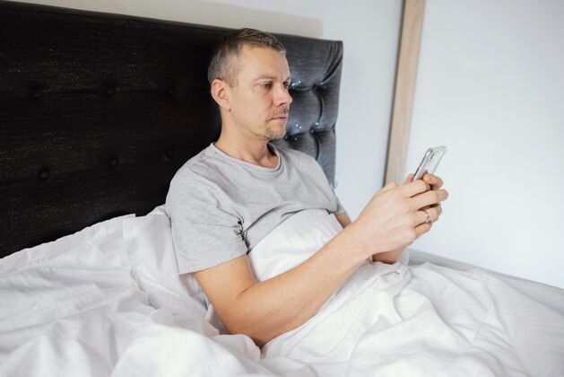 电话男人在床上用手机设备手机卧室