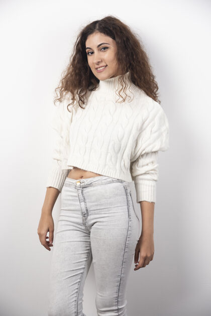 成人穿着白色毛衣的年轻女子站在白色的墙上高质量的照片青少年人年轻